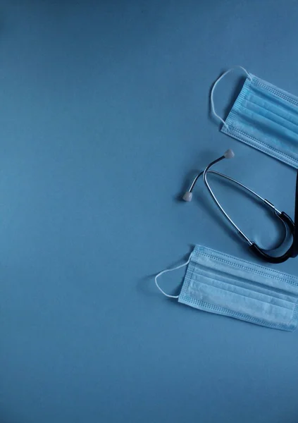 青い背景の医療用マスクと聴診器の背景にはコピースペースの文字が書かれています — ストック写真
