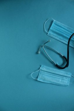 Tıbbi maskenin ve steteskopun arka planı mavi bir arkaplanda ve metin için bir yer var.