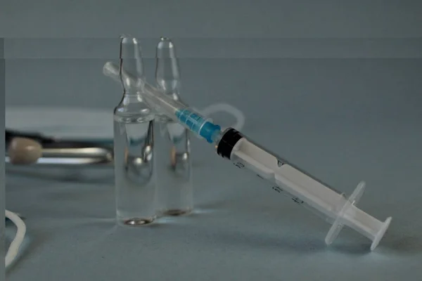 Aşılanmış şırınga ve mavi bir zemin üzerinde lekart aşısı olan iki şişe..