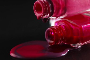 Tırnak cilasının akan damlaları. Kırmızı bordo kırmızı, siyah bir arka planda makro plan..