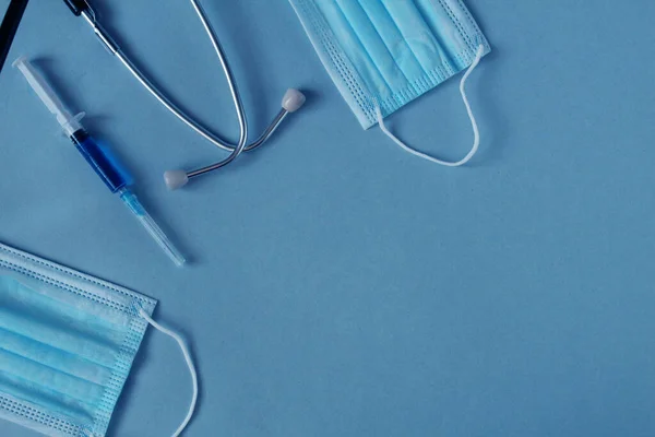 扁平的药物背景注射器口罩听诊器躺在蓝色的背景上 上面有一个可以看到文字的地方 — 图库照片