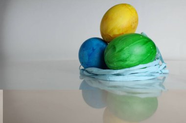 Üç renkli mavi yeşil yumurta, Von Paskalya 'nın yanından kopyalanmış beyaz bir zemin üzerinde yuva yapar..