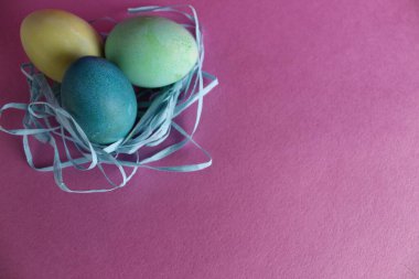 Paskalya arkaplanında üç tane çok renkli yumurta pembe arka planda metinler için yeri olan şekerdir..