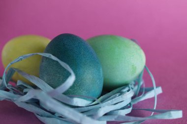 Paskalya arkaplanında üç tane çok renkli yumurta pembe arka planda metinler için yeri olan şekerdir..