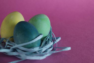 Paskalya arkaplanında üç tane çok renkli yumurta pembe arka planda metinler için yeri olan şekerdir..