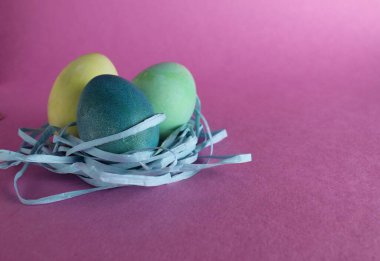 Paskalya arkaplanında üç tane çok renkli yumurta pembe arka planda metinler için yeri olan şekerdir..