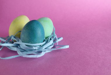 Paskalya arkaplanında üç tane çok renkli yumurta pembe arka planda metinler için yeri olan şekerdir..