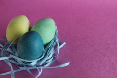 Paskalya arkaplanında üç tane çok renkli yumurta pembe arka planda metinler için yeri olan şekerdir..