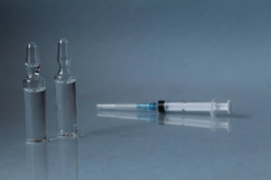 Mavi arka planda şırınga ilacı olan küçük bir aşı..