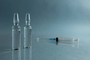 Mavi arka planda şırınga ilacı olan küçük bir aşı..