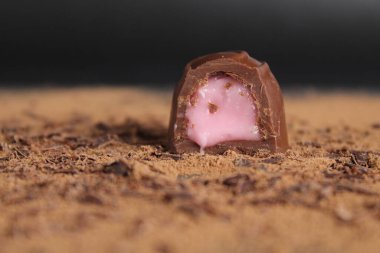 Çikolata Günü, çikolatalı şekerlemeleri siyah bir arka planda kakaonun üzerine koyuyor. Kahverengi çikolatalı arka planda mesajlaşacak bir yer var..