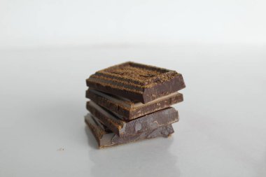 Koyu acı çikolata parçaları yığılmış beyaz bir zemin üzerinde uzanır metin ve kopyalanacak bir yeri olan bir yansıma ile.