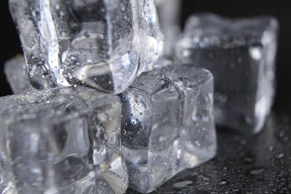 Ice cubes melt lie on a black background with a text close-up.