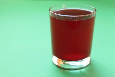 Kırmızı içecek suyu ya da yeşil arka planda bir bardakta komposto metin ve kopyalanacak bir yer..