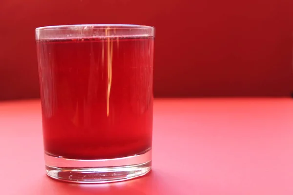 red drink of milky preparation of raspberry blueberries or kulbnik mors juice compote on a red background with a place for text and copyspace.