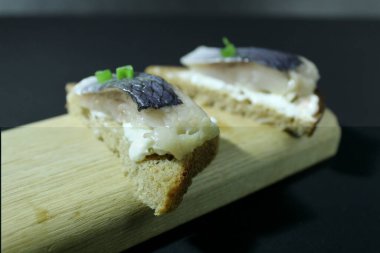 Tahta bir tahtanın üzerinde balık parçaları soğan yeşillikleri ve siyah bir zemin üzerinde salatalık ve metin ve kopyalama alanı olan bir yer..