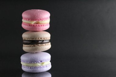 Siyah parlak bir arkaplanda, metin ve kopyalanacak bir yeri olan üç badem kurabiyesi..