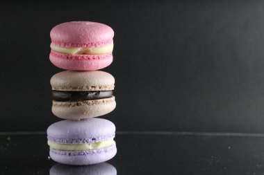 Siyah parlak bir arkaplanda, metin ve kopyalanacak bir yeri olan üç badem kurabiyesi..