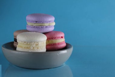 Makaronlar lavantalı, çikolatalı, pembe kahve mavi bir arka planda gri bir tabakta ve kopyalanmış uzayın metnini ekleyecek bir yerde.