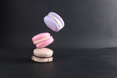 Siyah bir zemin üzerinde uçan üç badem kurabiyesi ve metin ve kopyalanacak bir yer..