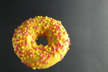 Siyah bir zemin üzerinde sarı jöleli uçan yiyecek donutu berberi metin ve kopyalanacak bir yer var..