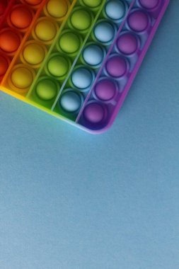 Stres önleyici oyuncak popit mavi arka planda basit bir gamze, mesaj atılacak bir yer ve kopyasıyla. Yukarıdan görüntüle.