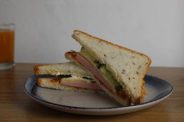 Sosisli, salatalıklı öğle yemeği sandviçi bir fincan çay ya da kahvenin yanında duruyor. Sabah servisi. Hazırlık. Cafe Restoranı.