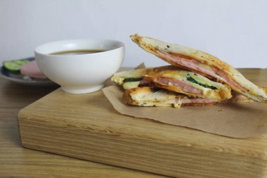 Sandviç tepsisinde kahvaltı. Yanında da ahşap tepside salam peyniri ve çay. Odaya kahvaltı var. Sabah kahvesi.