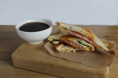 Sandviç tepsisinde kahvaltı. Yanında da ahşap tepside salam peyniri ve çay. Odaya kahvaltı var. Sabah kahvesi.