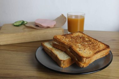 Yemek, avtrak. Jambonlu ve sebzeli sandviçler masada portakallı kayısı suyunun yanında gri bir tabakta yatar. Kahvaltı hazırlıyorum..
