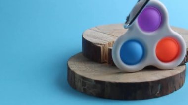 Kamera oyuncak anti-sressing popit yaklaşır basit bir gamze aşağı ahşap bir standın vasiyeti mavi bir arka planda.