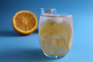 Adım adım limonata yapmak için. Adım 2. Meyve portakalını soda ile doldur. Mavi arka planda bir bardak portakallı limonata ve mesaj için bir yer. yakın plan.