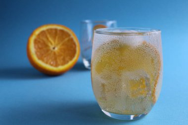 Adım adım limonata yapmak için. Adım 2. Meyve portakalını soda ile doldur. Mavi arka planda bir bardak portakallı limonata ve mesaj için bir yer. yakın plan.