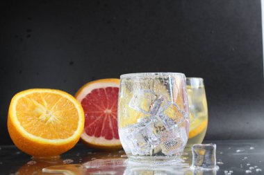 Siyah arka planda bir bardak buz ve meyve portakalı greyfurt içinde limonata suyu pişirmek. Yaz içkileri. Limonata içeceği..