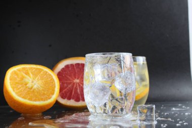 Siyah arka planda bir bardak buz ve meyve portakalı greyfurt içinde limonata suyu pişirmek. Yaz içkileri. Limonata içeceği..