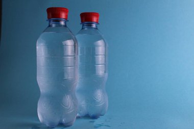 Mavi arka planda plastik şişelerde mineralli su içmek. Metnin yeri ve fotokopisi var. Saf su. Soğuk meşrubat. Tazeleniyor.