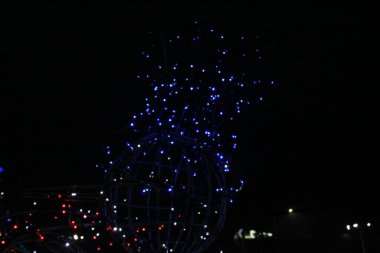 Koyu siyah arka planda mavi çelenkler. Yılbaşı arifesi geçmişi. Neşeli ışıklandırma.