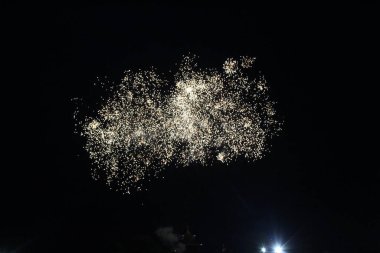 Havai fişeklerin başlangıcı karanlık gökyüzünde ışık saçar. Havai fişeklerin ilk gülleri.