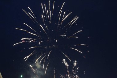 Havai fişekler, beyaz parlayan ışıkları selamlıyor. Siyah arka planda beyaz bir ışık yükseldi. Şenlikli atmosfer Yeni Yıl Noel Bağımsızlık Günü.