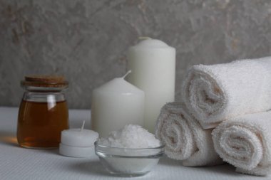 Spa, soya gövdesi için masaj evi bakımı. Beyaz mumlar, kavanozdaki yağlı havlular, beyaz gri bir arka planda, mesaj için yeri olan fırçalar. Güzellik salonu..