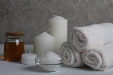 Spa, soya gövdesi için masaj evi bakımı. Beyaz mumlar, kavanozdaki yağlı havlular, beyaz gri bir arka planda, mesaj için yeri olan fırçalar. Güzellik salonu..