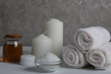 Spa, soya gövdesi için masaj evi bakımı. Beyaz mumlar, kavanozdaki yağlı havlular, beyaz gri bir arka planda, mesaj için yeri olan fırçalar. Güzellik salonu..