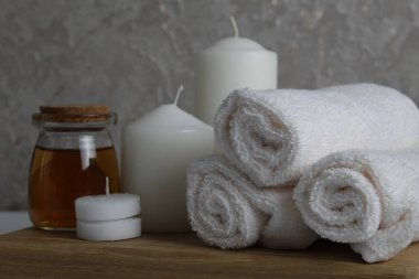 Spa, soya gövdesi için masaj evi bakımı. Beyaz mumlar, kavanozdaki yağlı havlular, beyaz gri bir arka planda, mesaj için yeri olan fırçalar. Güzellik salonu..