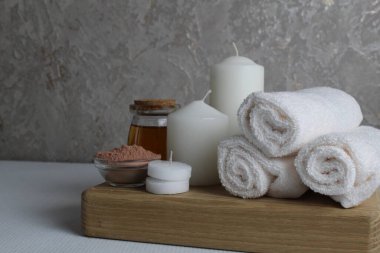 Spa, soya gövdesi için masaj evi bakımı. Beyaz mumlar, kavanozdaki yağlı havlular, beyaz gri bir arka planda, mesaj için yeri olan fırçalar. Güzellik salonu..