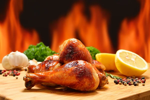 Grilled chicken legs and various vegetables on a chopping wood — Stock Photo, Image