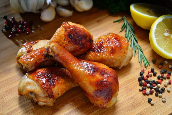 Pernas de frango grelhadas e vários legumes em uma madeira de corte — Fotografia de Stock