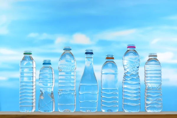 Fresh and clean drinking water in assortment of uncapped bottles on sky background