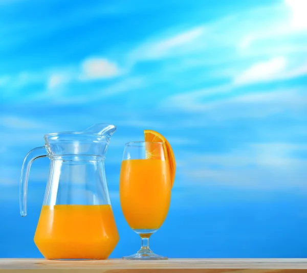 Sok pomarańczowy w dzbanku i szkło na tle nieba — Zdjęcie stockowe