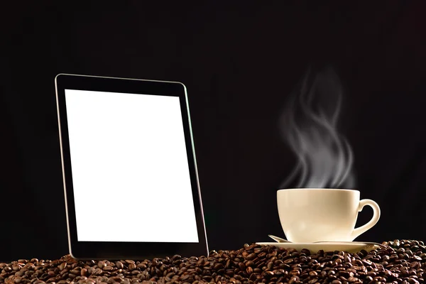 Компьютер с черно-белым экраном и чашкой кофе с дымом на стопке кофейных зерен — стоковое фото