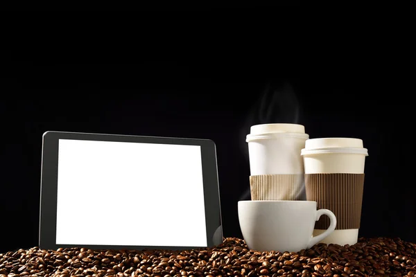 Компьютер с белоснежным экраном и чашками кофе с дымом на стопке кофейных зерен — стоковое фото